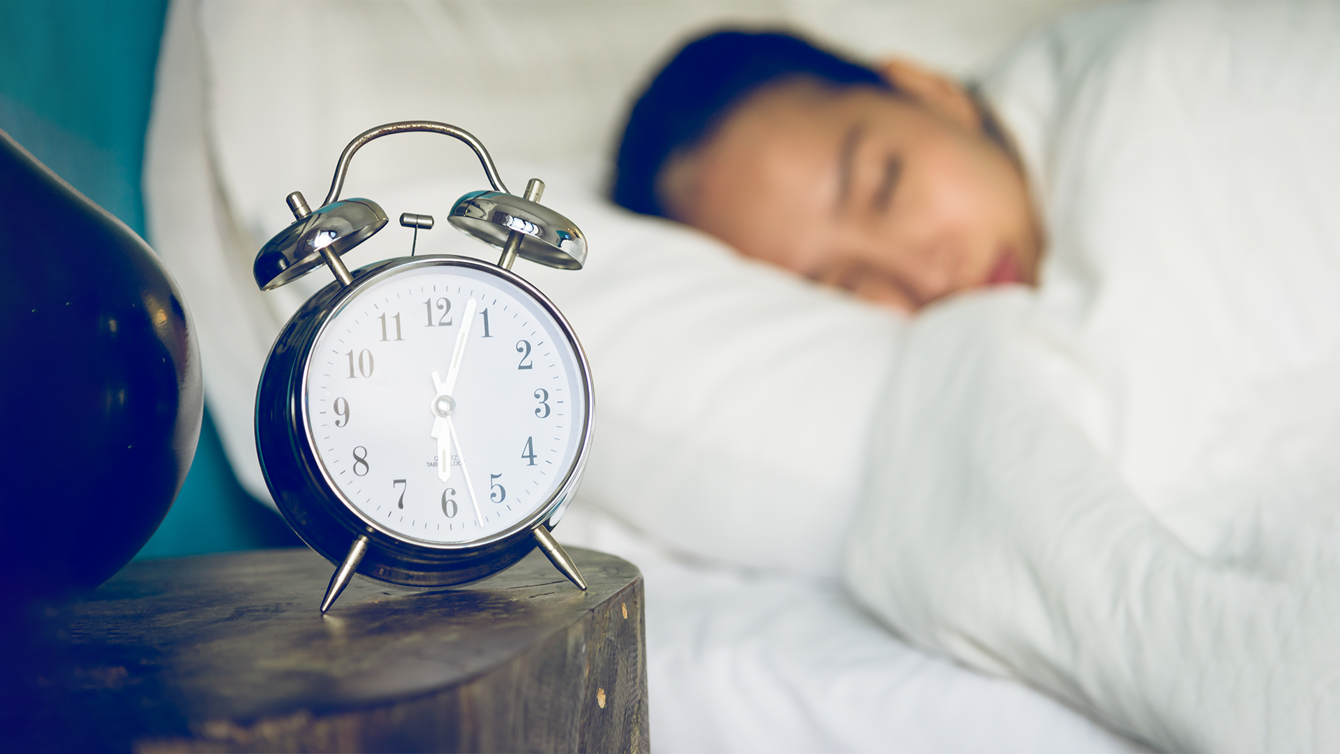 Person sleeping next to alarm clock 